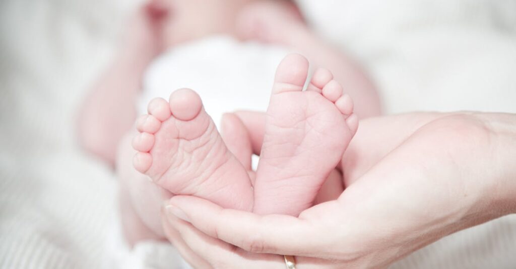 Tender photo of a mother's hands holding her newborn's feet, symbolizing love and care.