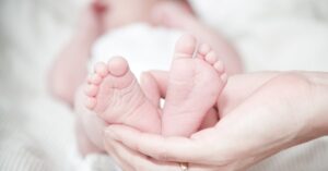 Tender photo of a mother's hands holding her newborn's feet, symbolizing love and care.